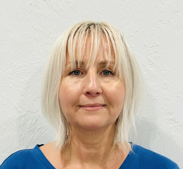 Anna Christodoulou, a blonde woman with bangs, smiles at the camera